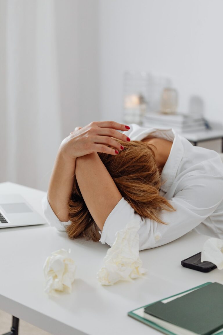 L'image montre une femme qui dort sur son bureau au travail.