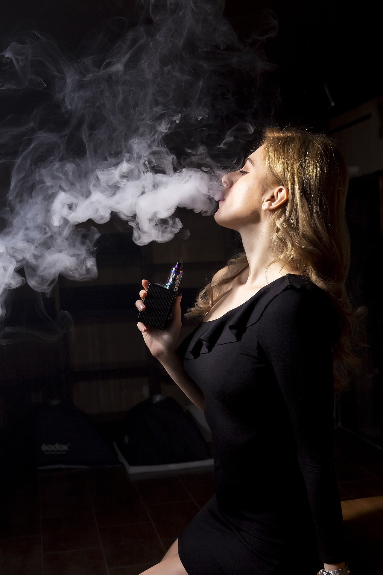 L'image montre une femme qui vapote et elle fait beaucoup de boucanes.